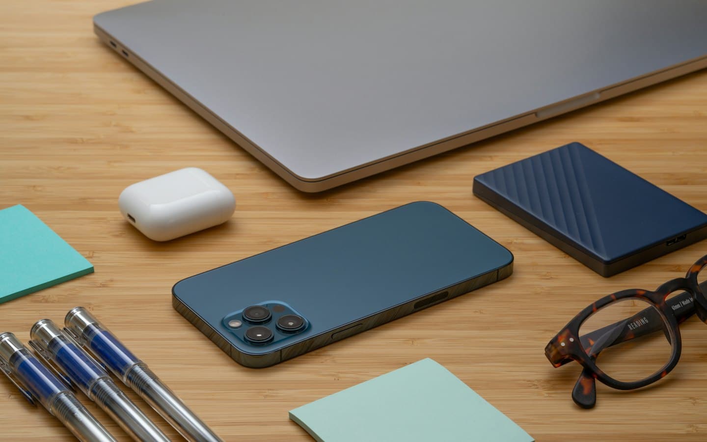 Neatly arranged modern desk items on a wooden surface.