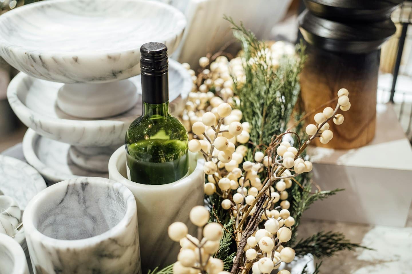 Marble bowls and containers arranged with greenery and berries.