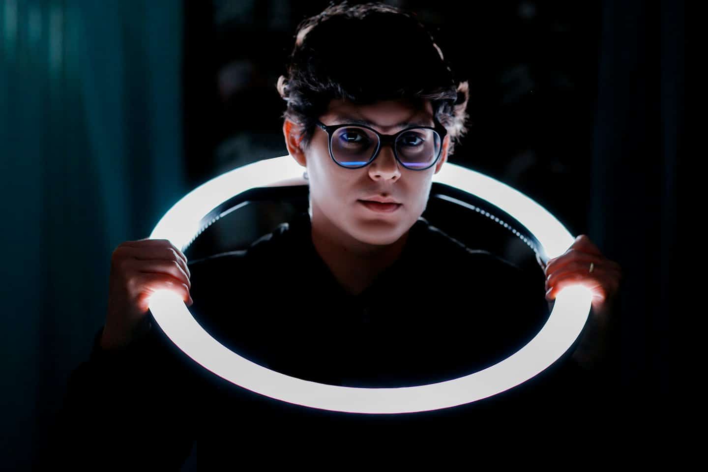Person holding a glowing LED ring light at chest height.